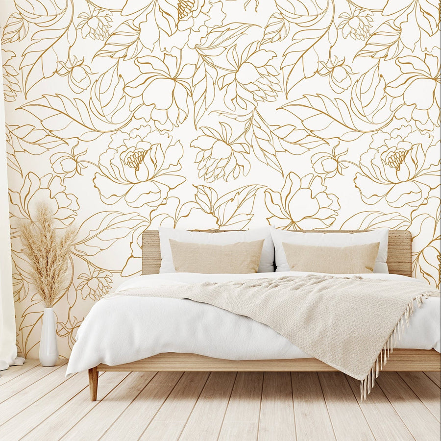 A neutral toned bedroom showing 'Florian' which is a white wallpaper featuring delicate gold outline illustrations of flowers and leaves in an elegant botanical repeating pattern.