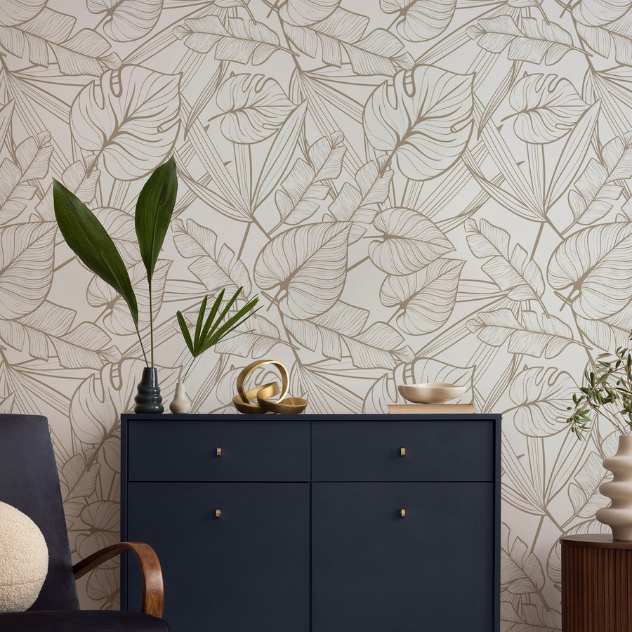 A living room with a navy side board showing 'Juniper Neutral' which is a white wallpaper featuring delicate gold tropical leaf outlines in a repeating botanical pattern with a modern minimalist design.